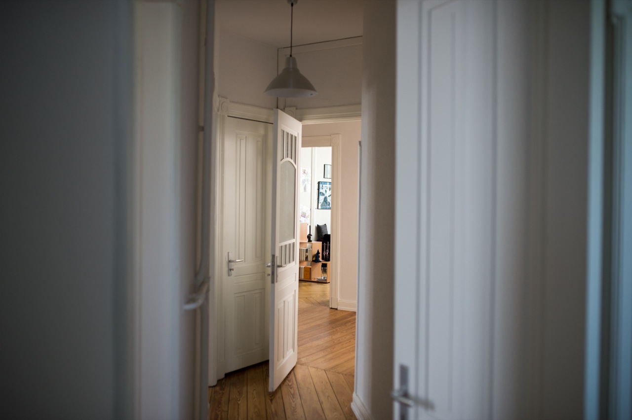 Blick durch einen Flur mit geöffneten weißen Türen und Holzboden in einer Wohnung