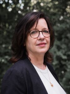 Porträt von Andrea Rinow vor grünem Hintergrund