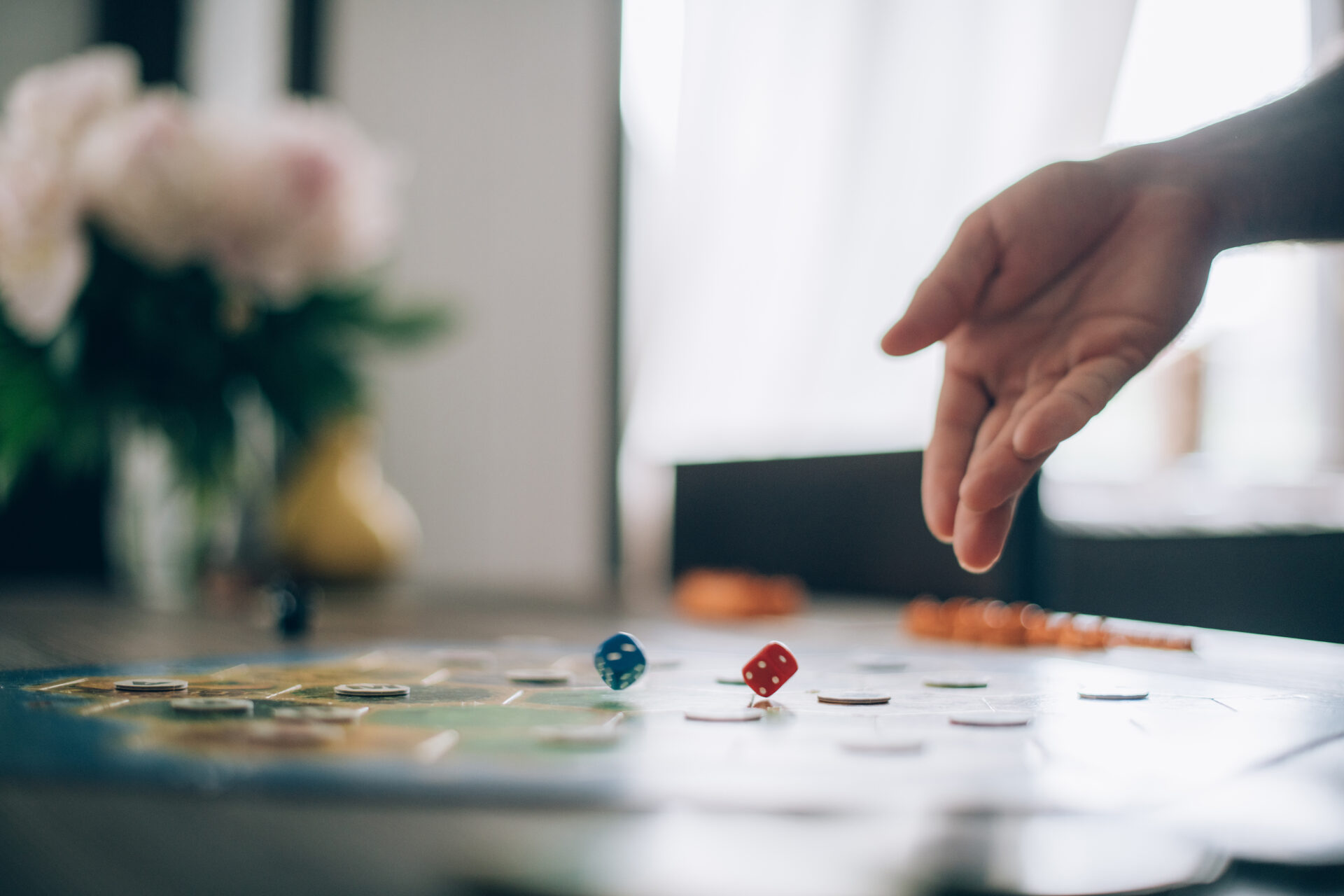 Hand über einem Spielbrett mit Würfeln und Spielsteinen
